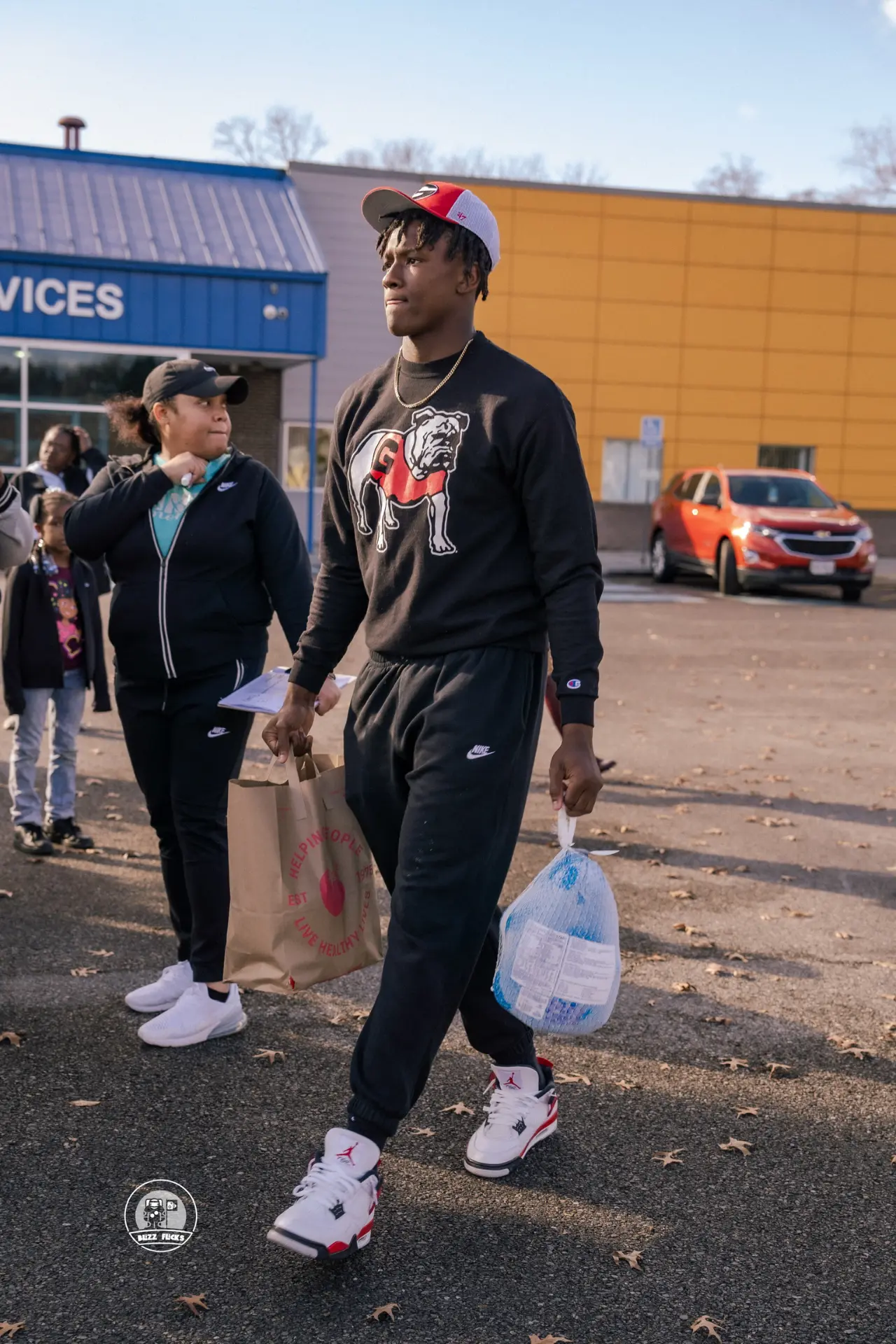 Chris Cole carrying a turkey and grocery bag to a family's car